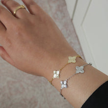 Load image into Gallery viewer, Close-up of a hand wearing a gold bracelet with butterfly charms on a patterned surface.